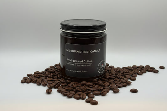 Jar of Meridian Street Candle Fresh Brewed Coffee candle surrounded by coffee beans on a light gray background