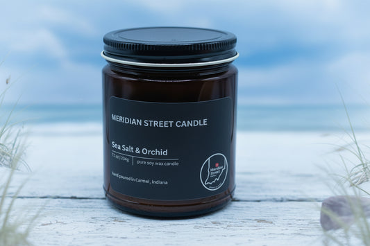 Black candle jar labeled 'Meridian Street Candle' with 'Sea Salt & Orchid' scent on a gray background