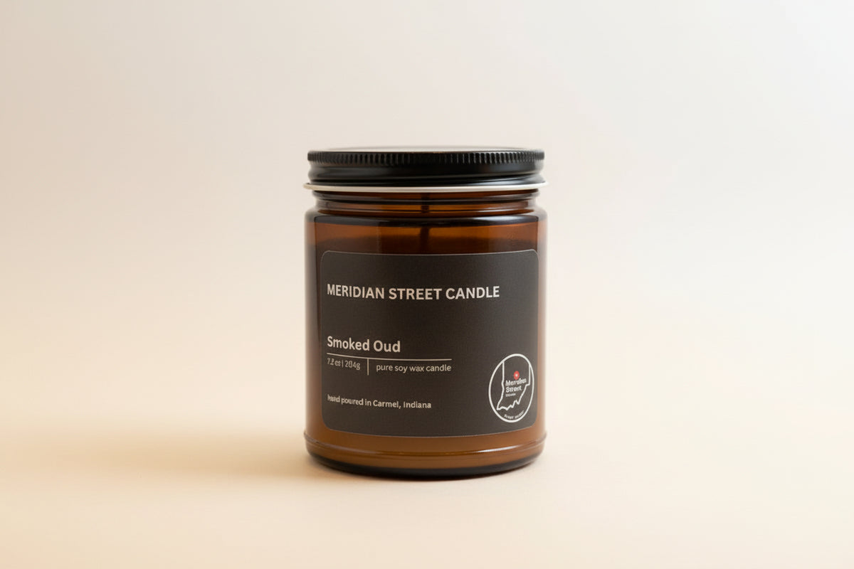 Black candle jar labeled 'Meridian Street Candle Smoked Oud' on a gray background